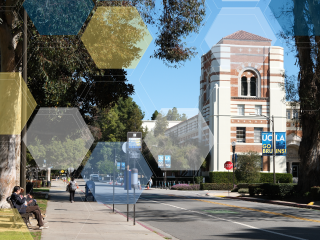 Blue UCLA Go Bruins! sign in front of a white and brick building. Trees on the right and left sides. 
